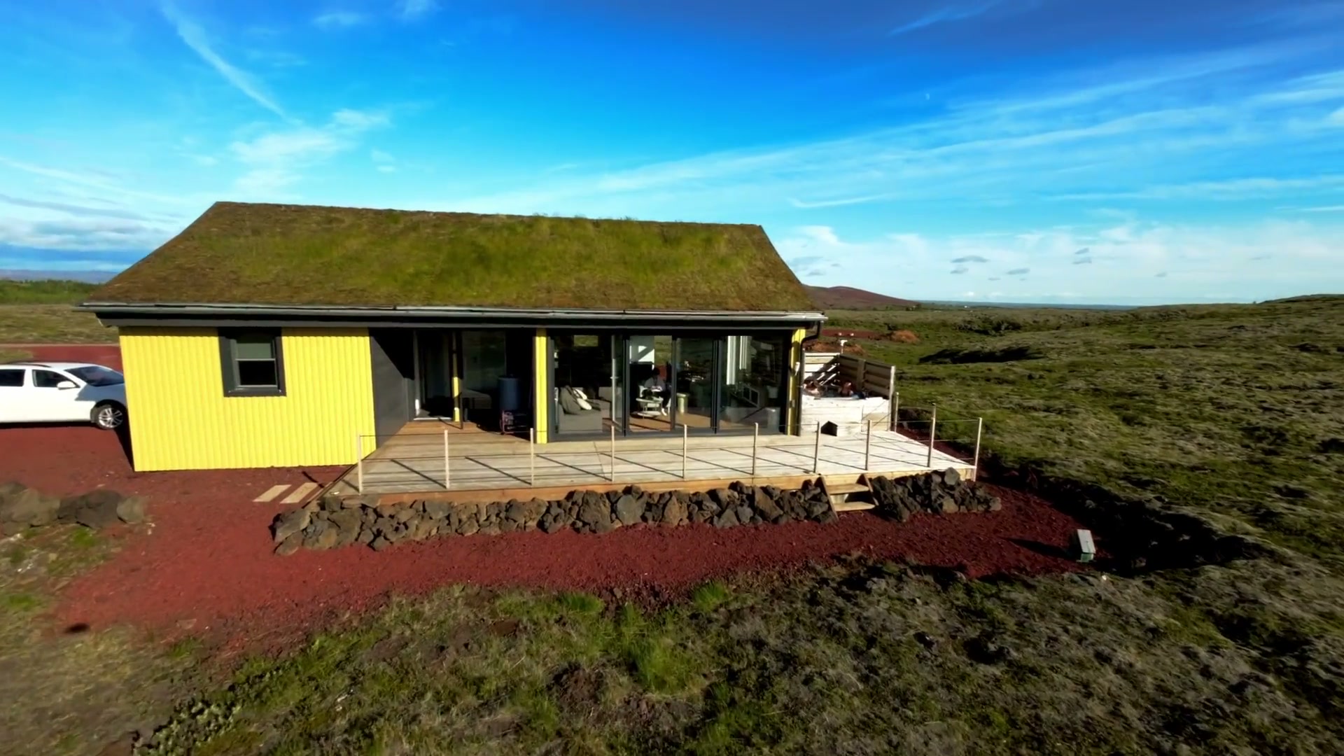The house from the air — deck running the full front beneath the turf roof, hot tub in the corner